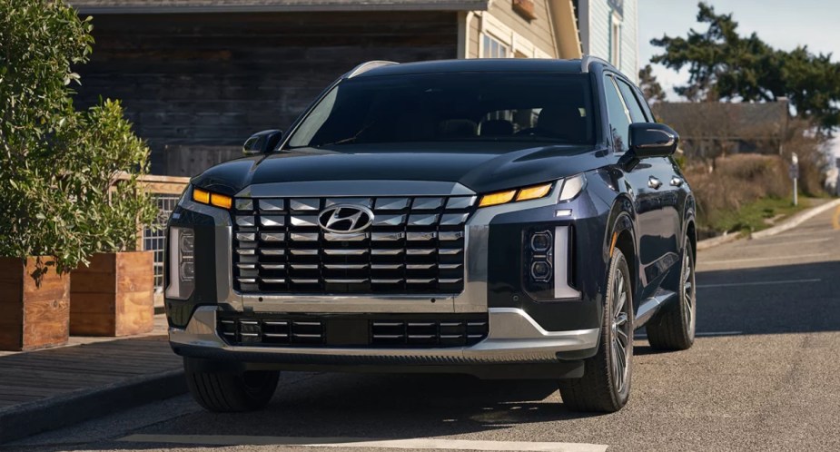 A blue 2023 Hyundai Palisade midsize SUV is parked on the road. 