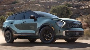 A green 2023 Kia Sportage small SUV is driving off-road.