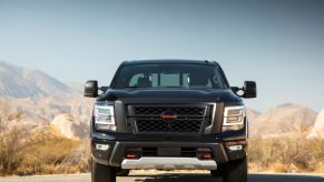 A front-facing shot of a black 2023 Nissan Titan full-size pickup truck model parked in a desert location