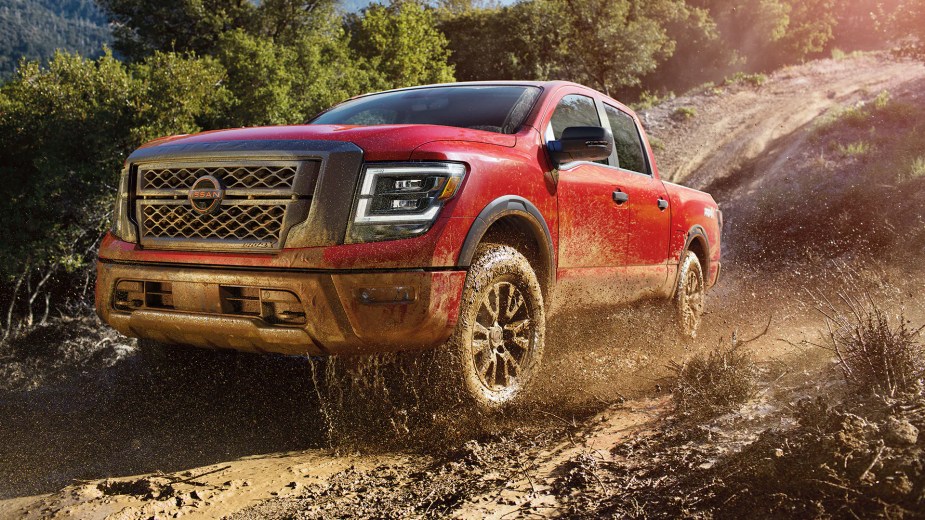 A red 2023 Nissan Titan drives through the mud.  How much will the full size truck cost you?