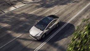 A white 2023 Toyota Prius driving down the road from an aerial view.