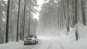 A car driving in snow where winter weather lowers fuel economy.