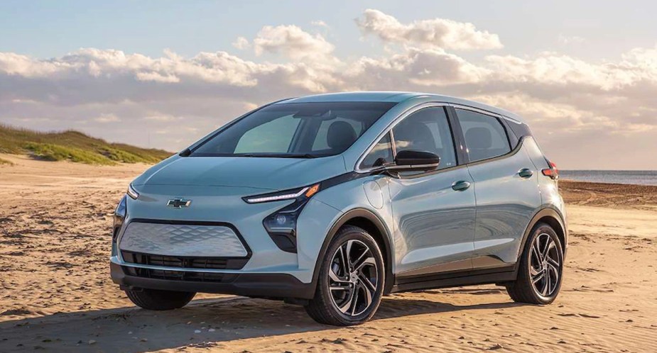 A gray 2023 Chevy Bolt EV is parked on the sand. 