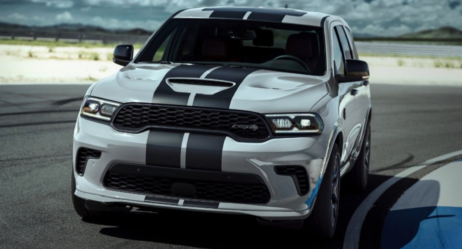 A white 2023 Dodge Durango SRT Hellcat midsize SUV is driving on a track. 