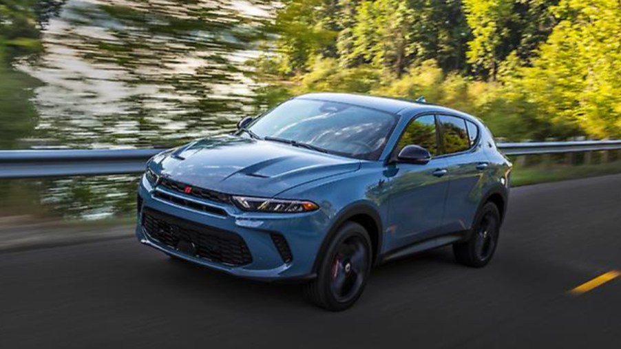 A blue 2023 Dodge Hornet small SUV is driving on the road.