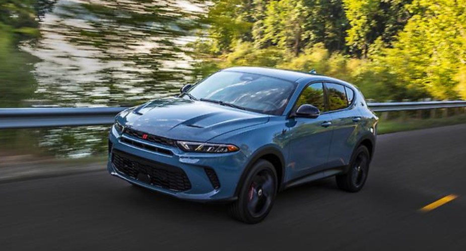A blue 2023 Dodge Hornet small SUV is driving on the road.