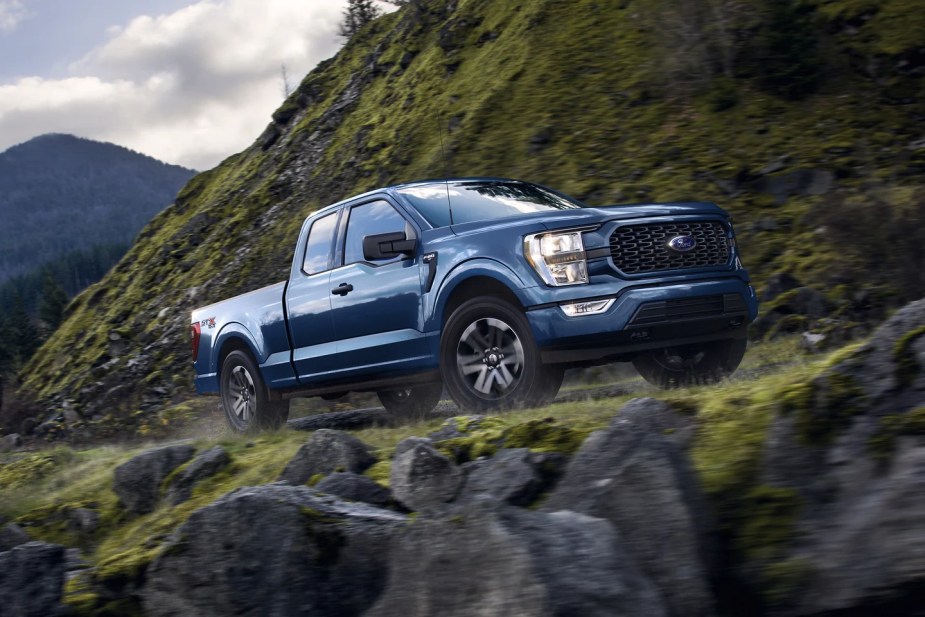 A 2023 Ford F-150 SuperCab is driving on a mountainous road.