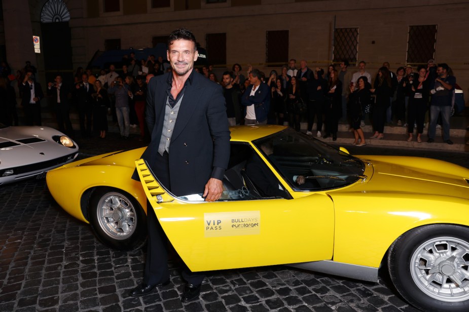 Frank Grillo standing in front of a classic Lamborghini GT car at the premiere of his Lamborghini film.