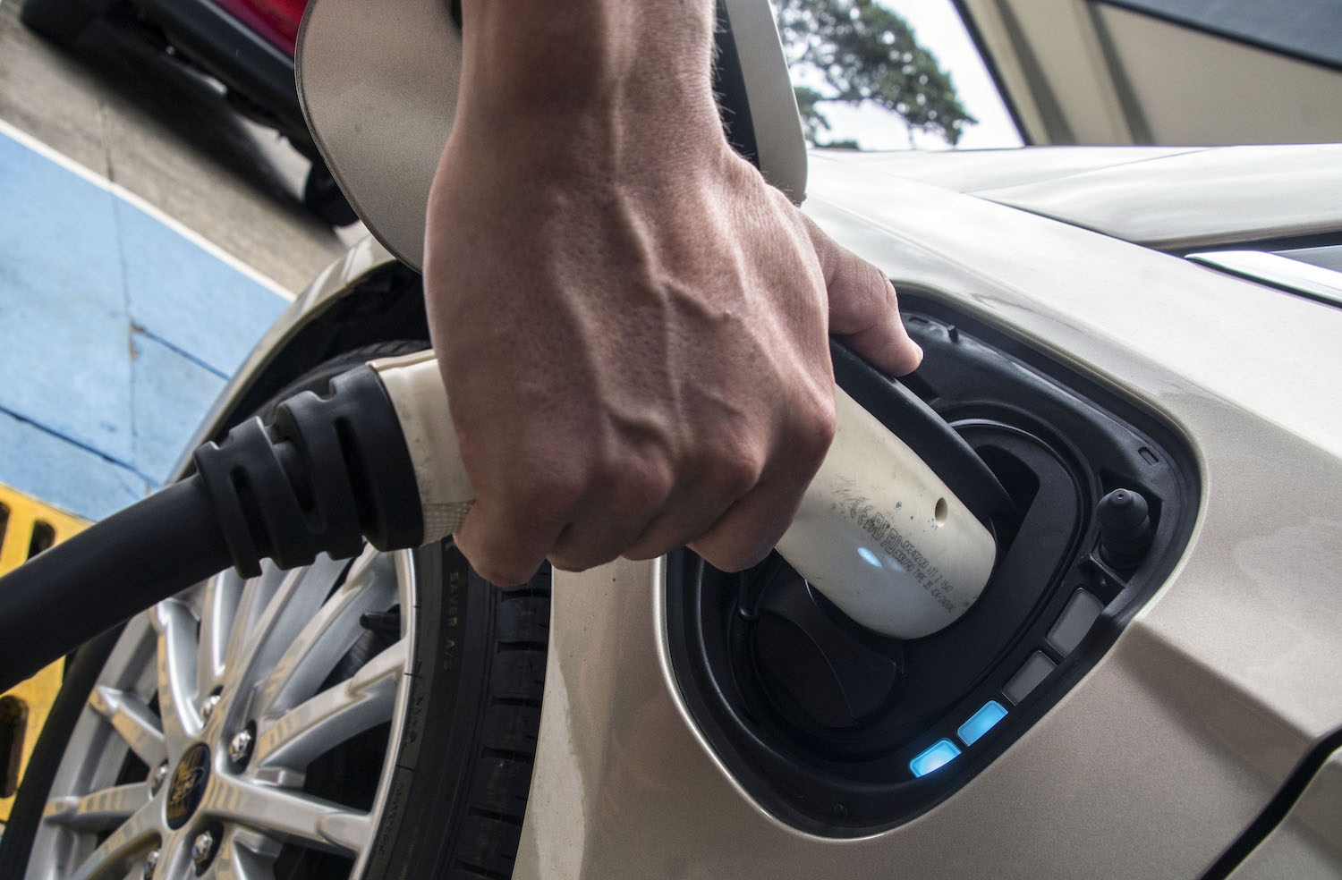 Closeup of the hand of Ford EV driver plugging in a cable to charge up their vehicle's battery.