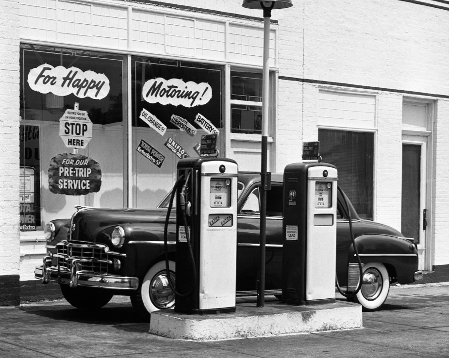 This is a classic service station that offers gas, car maintenance, and air for tires, with an old Dodge sedan parked out front.