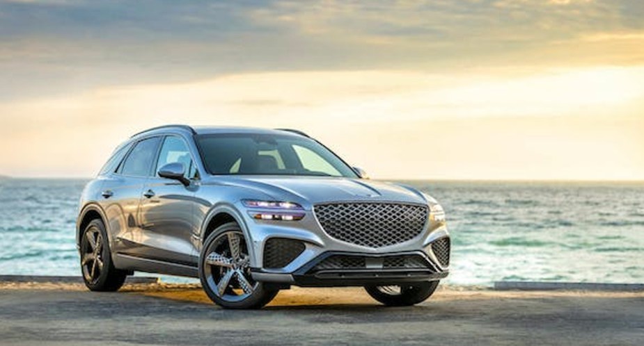 A gray 2023 Genesis GV70 luxury small SUV is parked on a beach. 