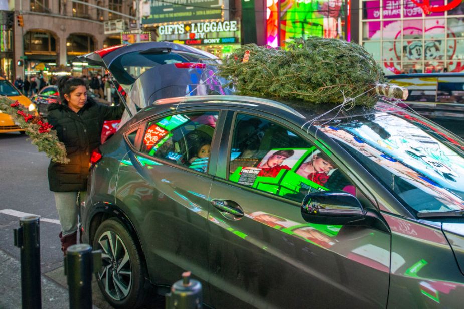 A Christmas tree tied ot a small SUV