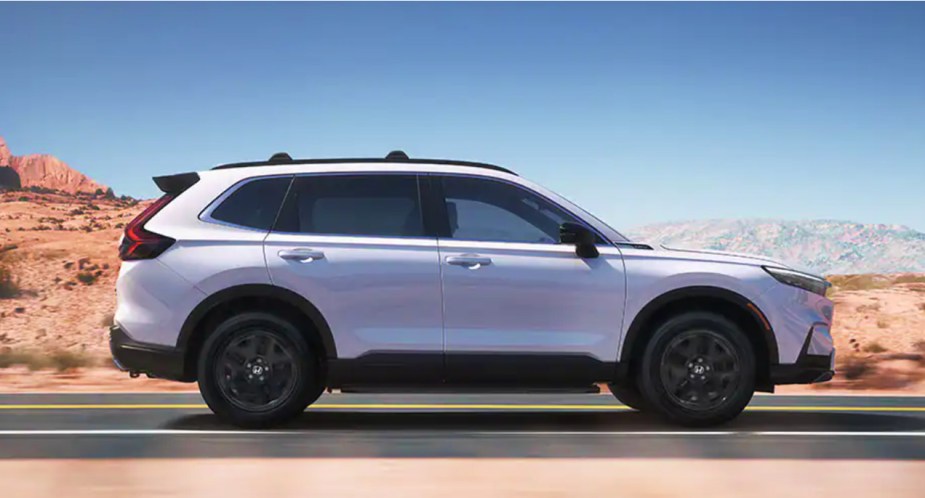 A white 2023 Honda CR-V small SUV is driving on the road. 
