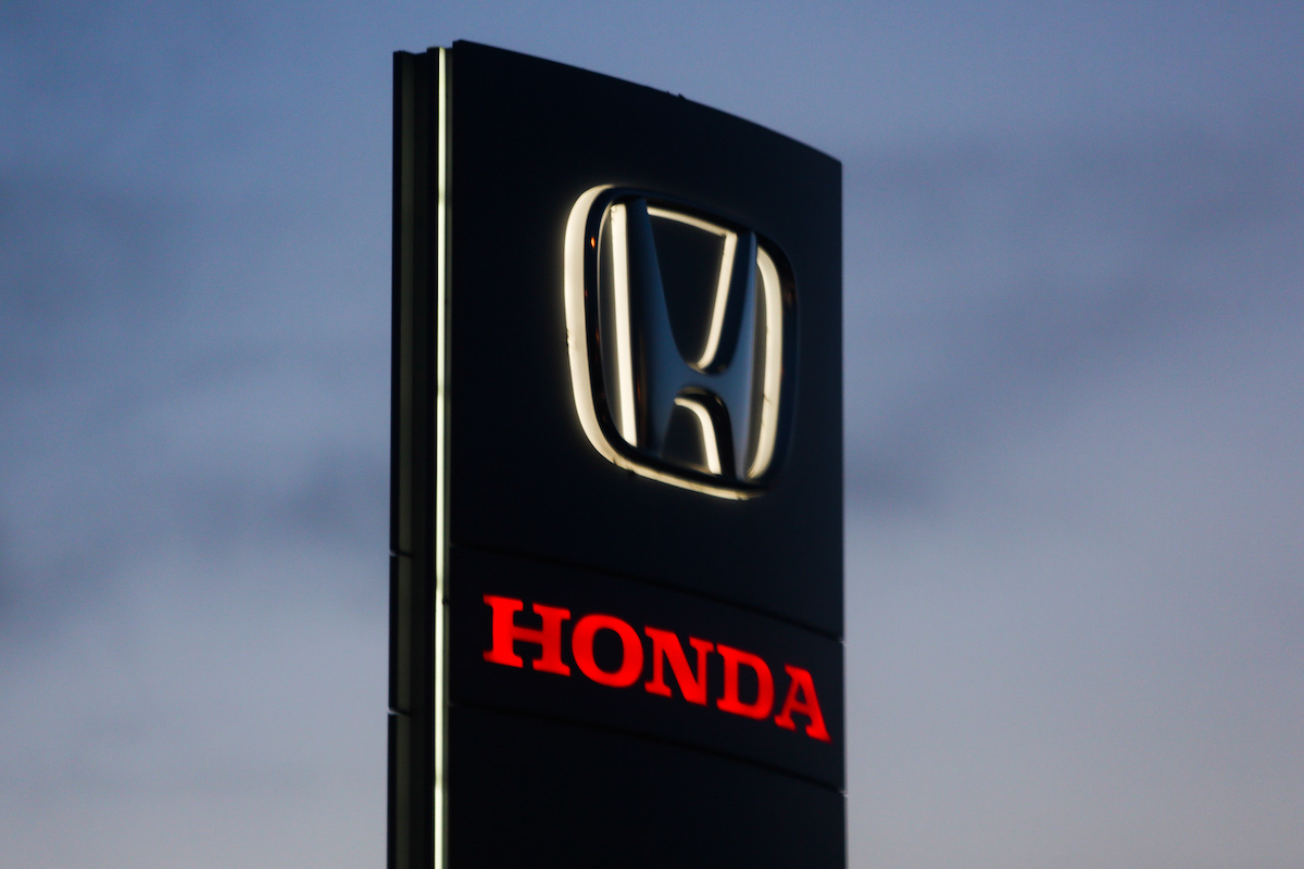A Honda sign illuminated at a car dealership.