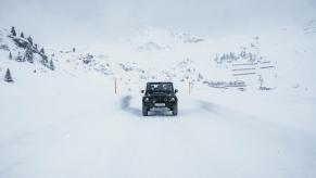 Promo photo of the Land Rover Defender based Ineos Grenadier SUV driving down a snow-covered road, mountains visible in the background.
