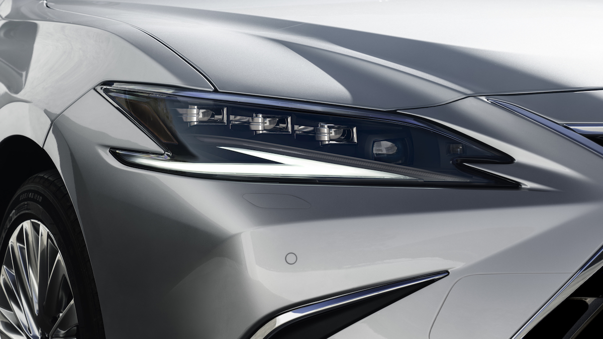The headlight of a silver Lexus ES luxury hybrid