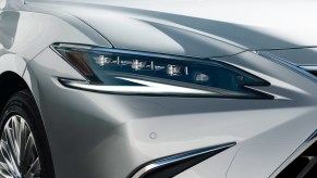 The headlight of a silver Lexus ES luxury hybrid