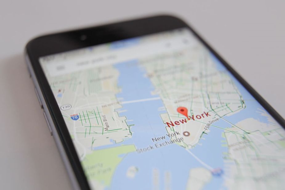 A phone accesses GPS to track a car and find a waypoint in New York.