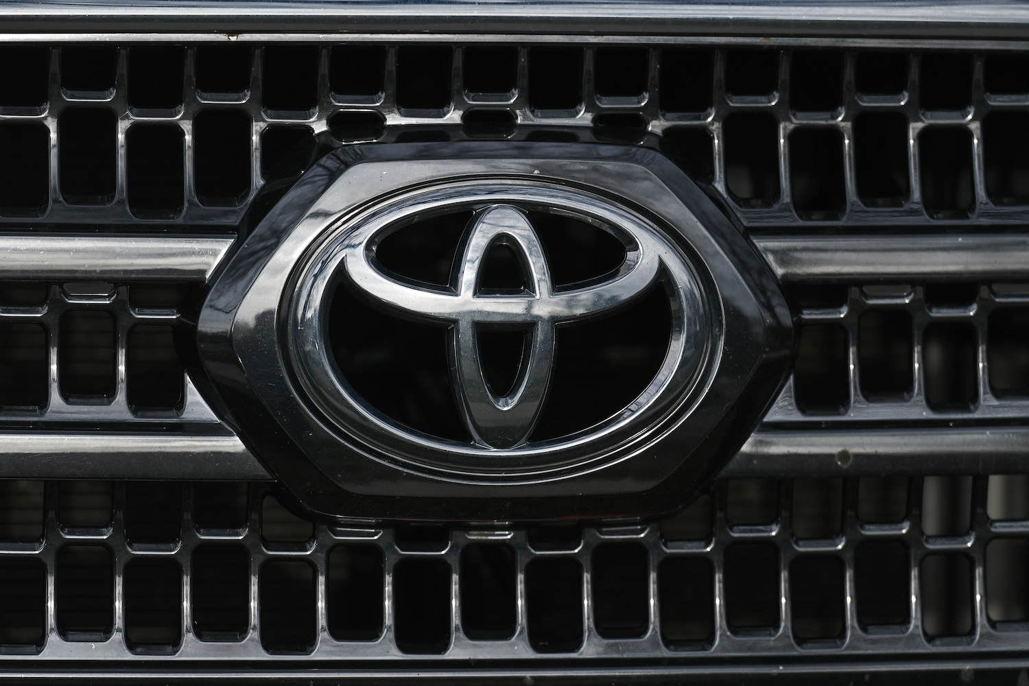 Close-up of the chrome Toyota Motor Corporation logo embedded in the front grille of a reliable used car.