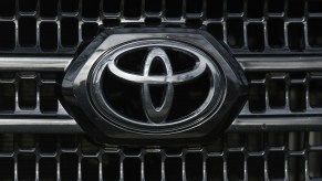 Closeup of the chrome Toyota motor corporation logo set into the grille of a reliable used sedan car.