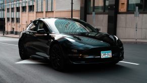A Black Tesla model driving down a city street