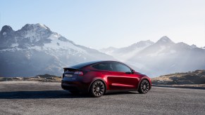 A red 2022 Tesla Model Y parked in front of a mountainside.