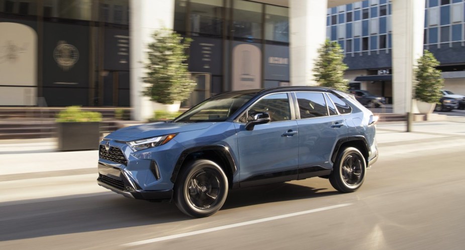 A blue 2023 Toyota RAV4 is driving on the road.
