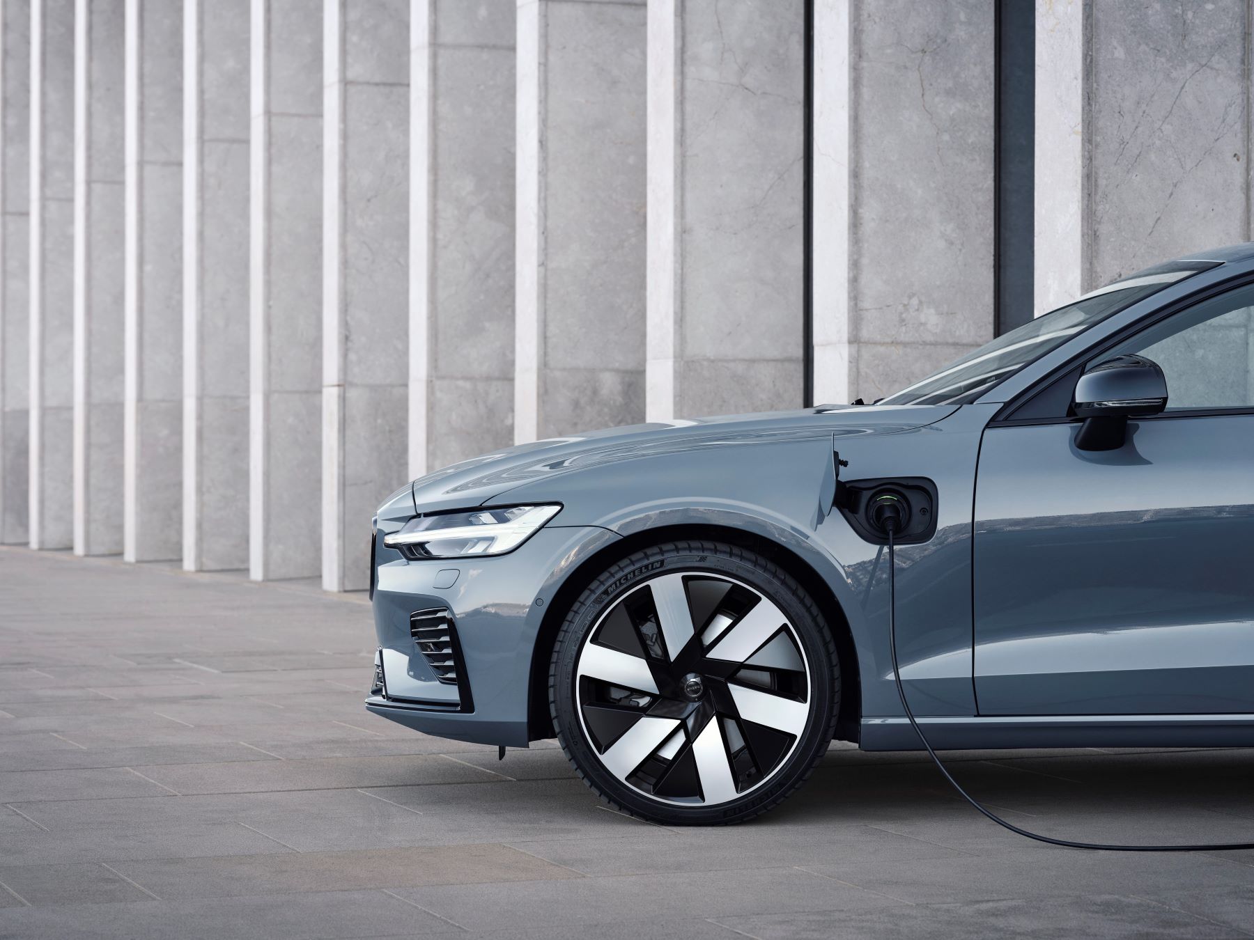 The Volvo S60 Recharge PHEV with a Thunder Grey color scheme plugged in and charging