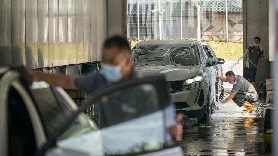 Workers washing cars, highlighting California car wash that cheated employees over $800k with $7 an hour wage