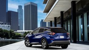 A blue 2023 Nissan Murano midsize SUV parked on a marble plaza near a pool in an urban city