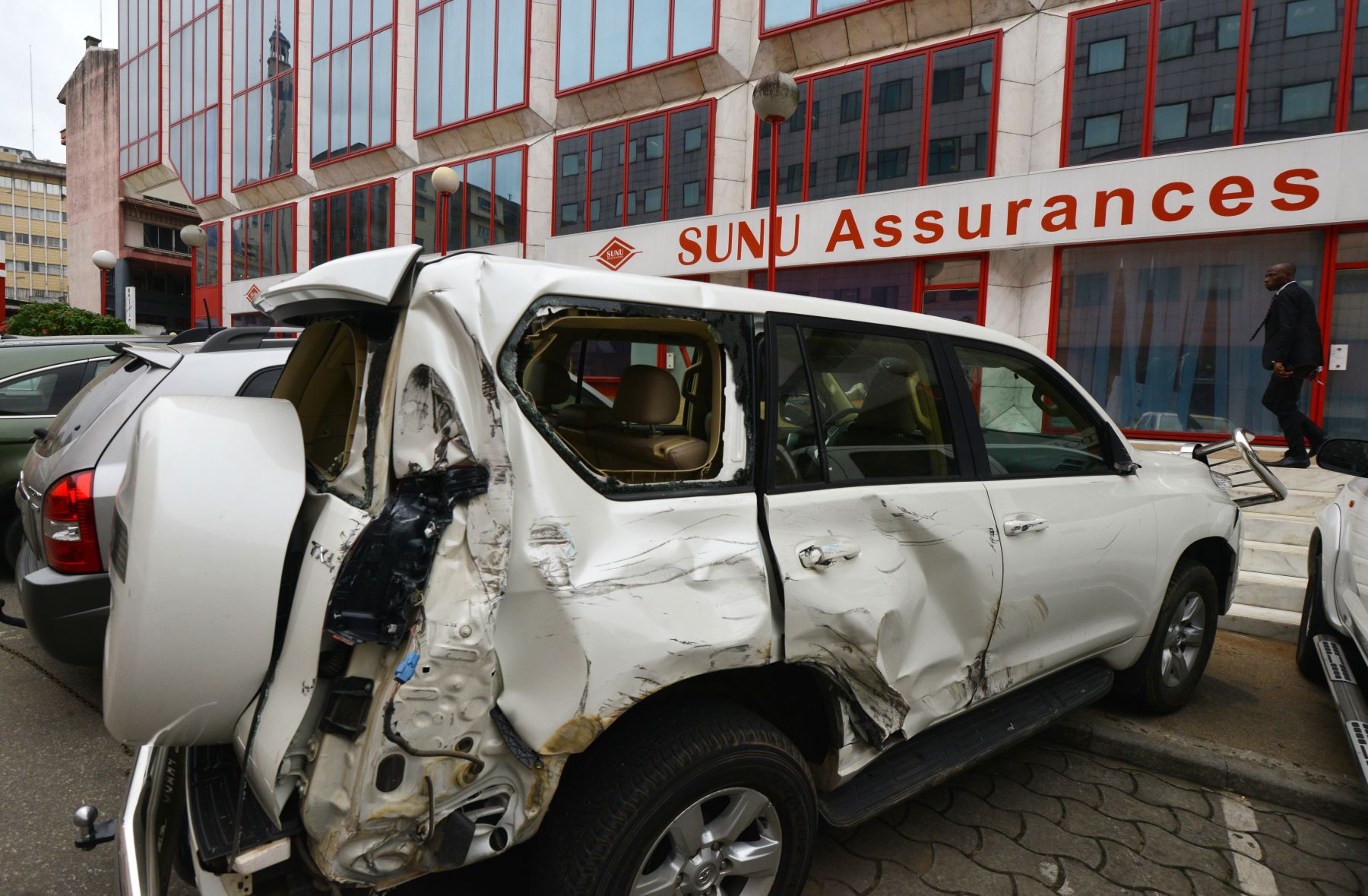 A damaged SUV parked in front of a SUNU Assurances insurance group office in Abidjan