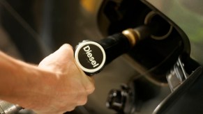 Closeup of a driver's hand as they pump fuel into the tank of their diesel engined car.