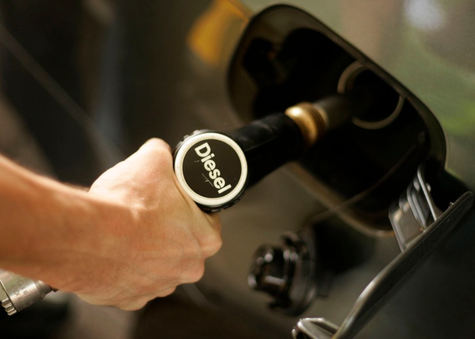 Closeup of a driver's hand as they pump fuel into the tank of their diesel engined car.