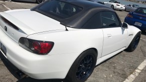 A white lowered Honda S2000 with rolled fenders.