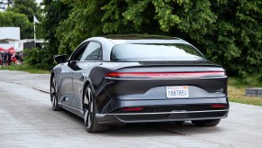 A Lucid Air electric car is shown on a paved road from the rear view.