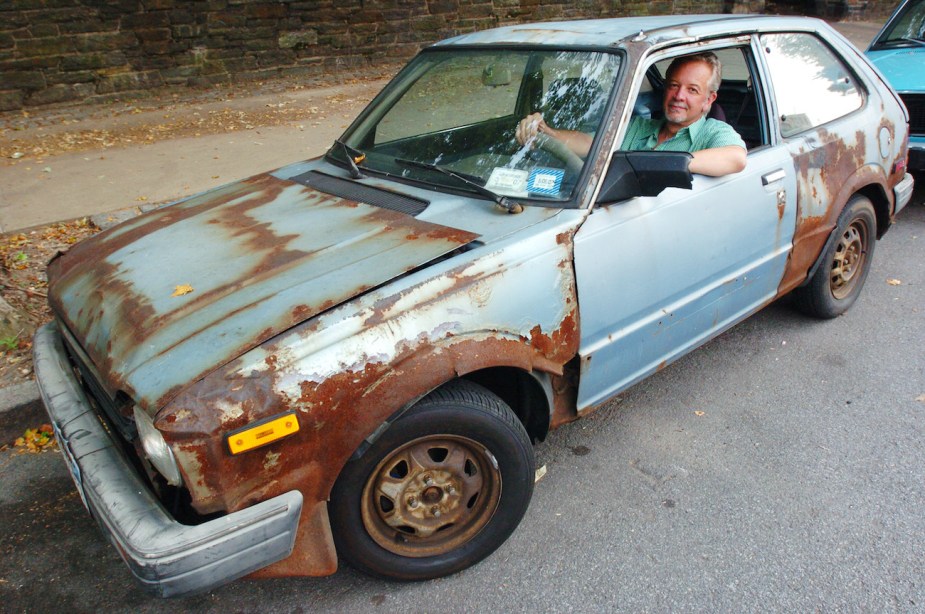 A man and his rusty Honda Civic.