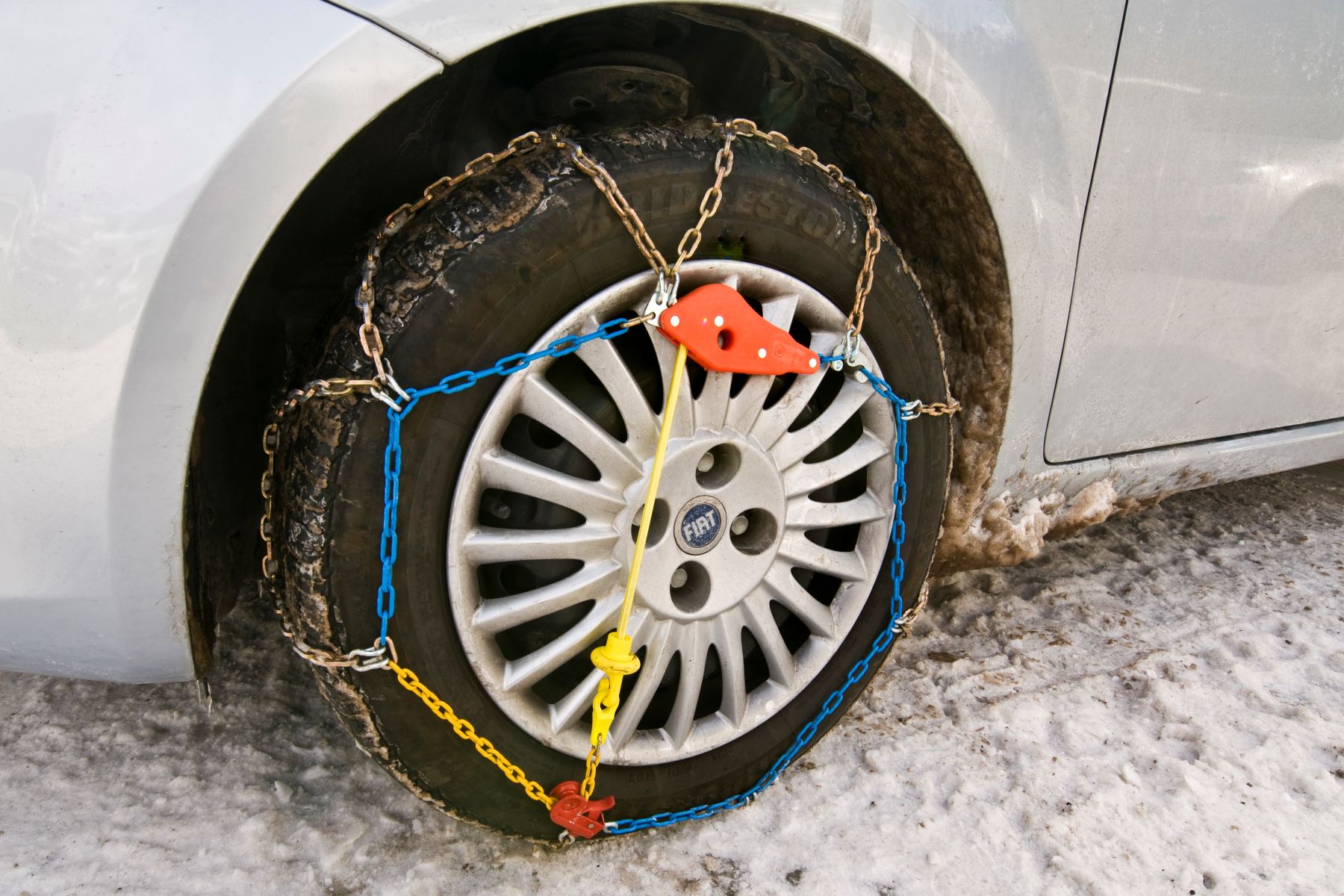 A Fiat car with a tire chain for winter and snowy weather driving conditions