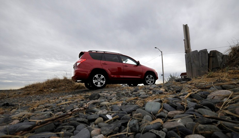 A red Toyota RAV4 is shown climbing a rocky hill