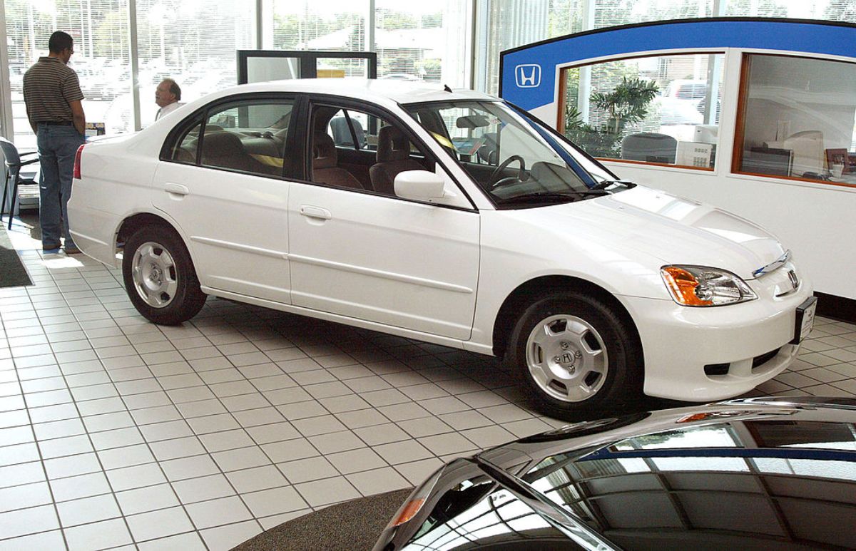A white 2003 Honda Civic Hybrid at a car dealership.