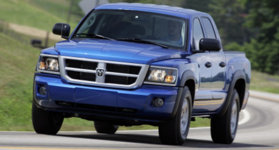 A blue 2008 Dodge Dakota midsize pickup truck is driving on the road. 
