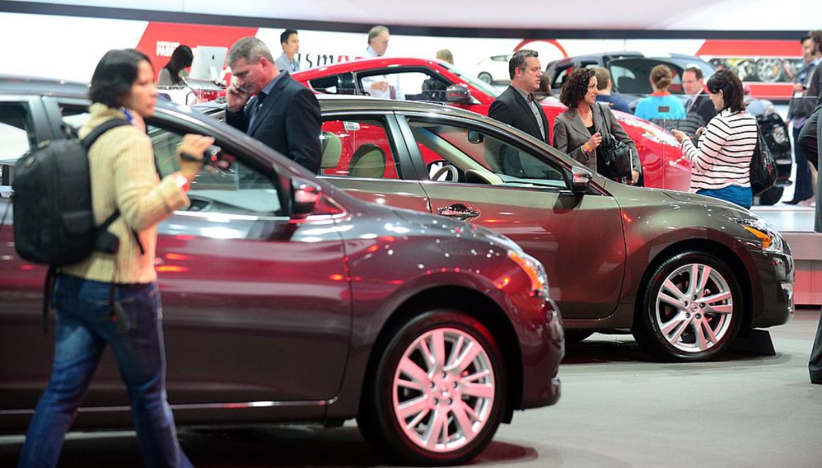 A person walking by a 2013 Nissan Sentra at an auto show.