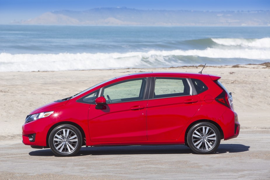 A Honda Fit hatchback in red poses by the beach.