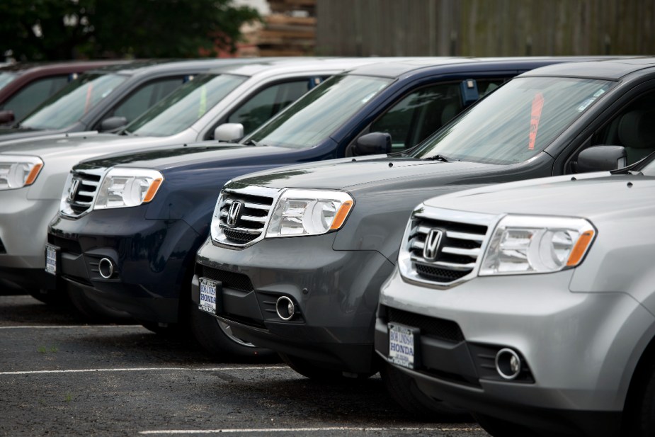 A group of Honda Pilot three-row SUV models are parked at a dealership.