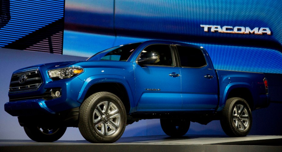 A blue 2016 Toyota Tacoma midsize pickup truck is on display at an auto show. 