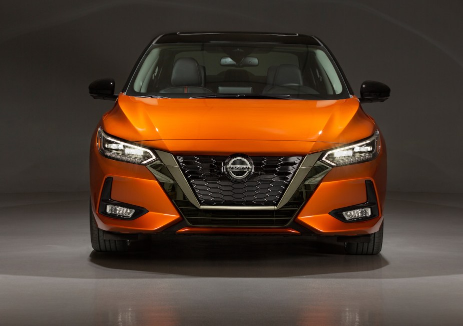 An orange Nissan Sentra in a black and grey room, which is one of the least reliable car models according to Consumer Reports.