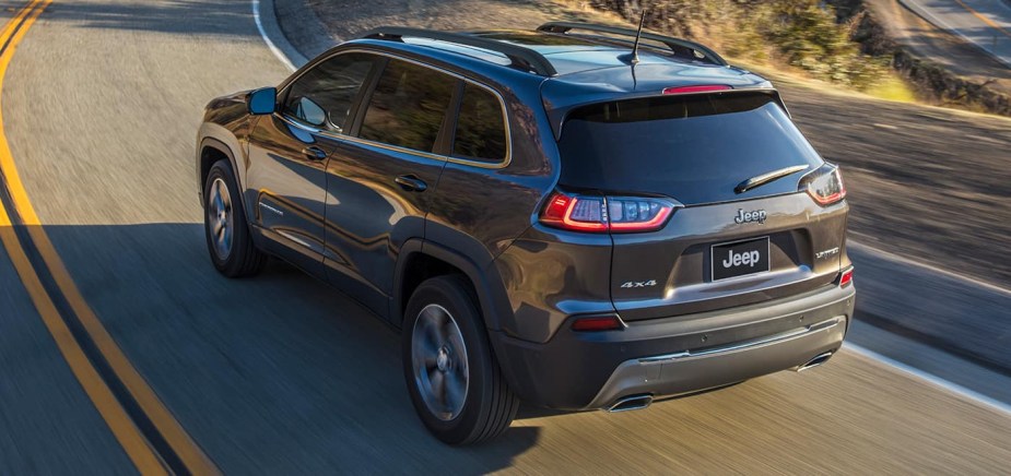 A gray 2022 Jeep Cherokee SUV driving at speed on a scenic road. 