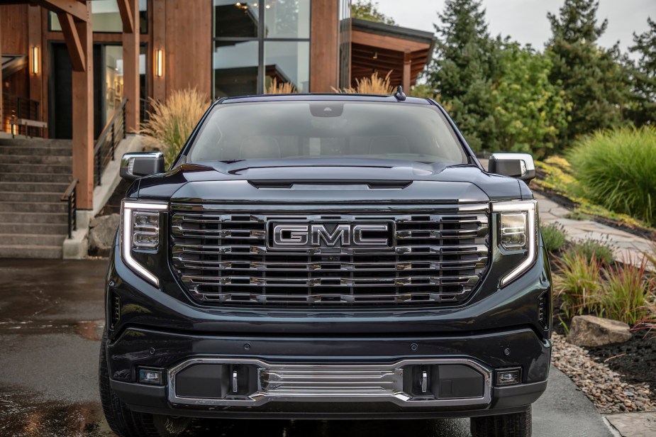 The grille of a GMC Sierra pickup truck that is parked in front of a house, its General Motors Company logo visible.