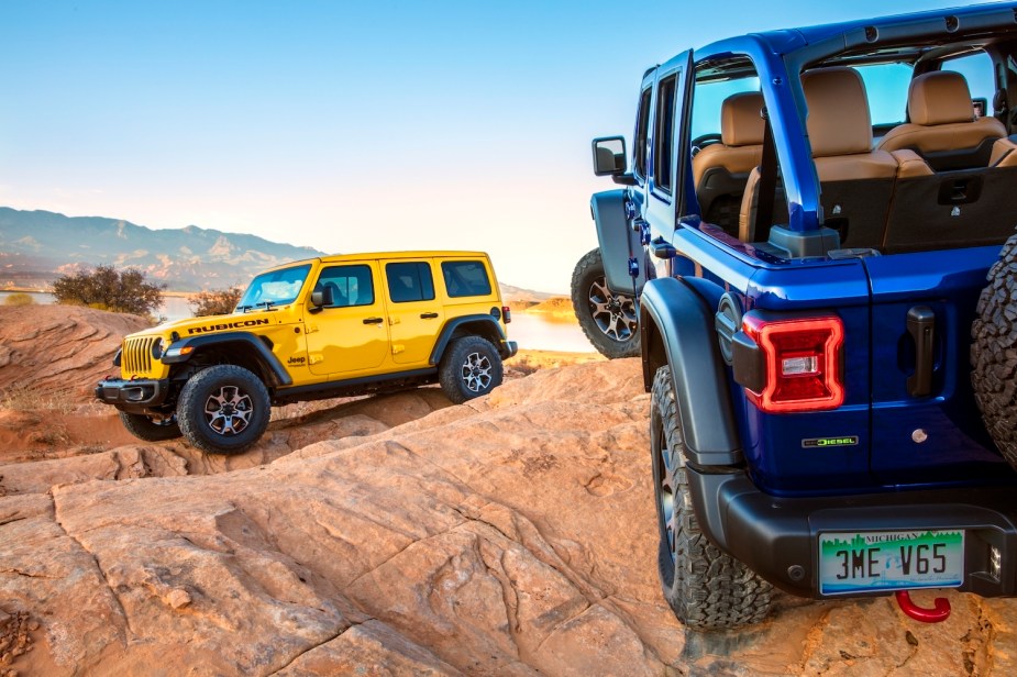 Yellow and blue Jeep Wrangler Rubicon SUV with Dodge Ram diesel V6 engines, parked on a rocky 4x4 trail for a promo photo.