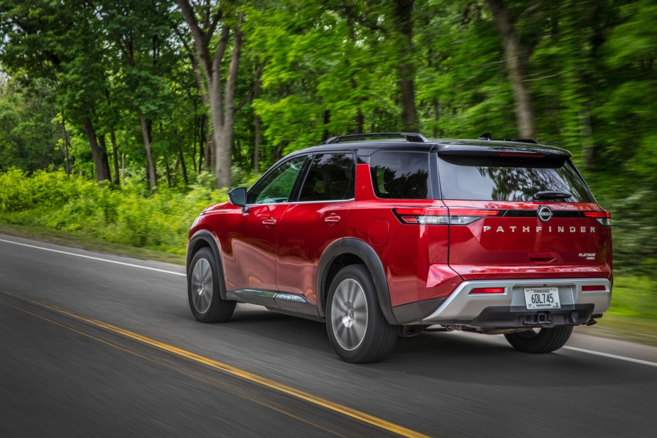 A 2022 Nissan Pathfinder driving down a wooded road, experts disagree on the midsize SUV's best trim.
