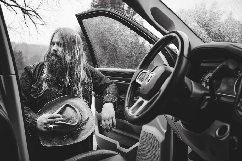 Chris Stapleton leaned against the door of a RAm pickup truck, the steering wheel visible in the foreground.